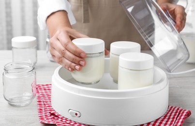 Photo of Woman making tasty yogurt at wooden table in kitchen, closeup