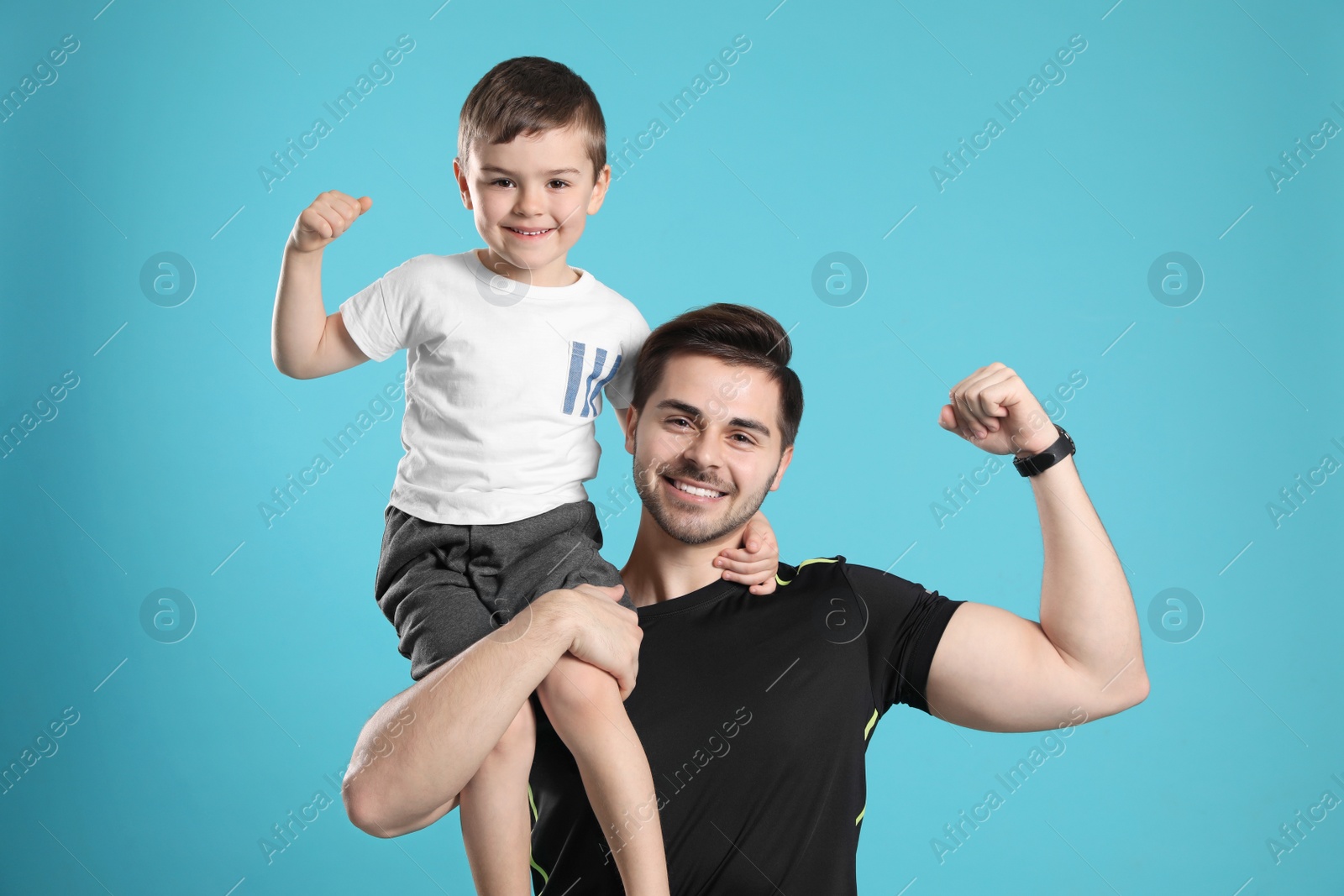 Photo of Portrait of sporty dad and his son on color background