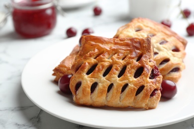 Fresh delicious puff pastry with sweet cherries served on white marble table, closeup