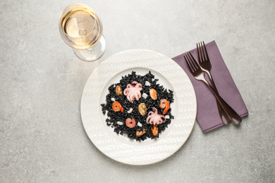 Photo of Delicious black risotto with seafood served on light grey table