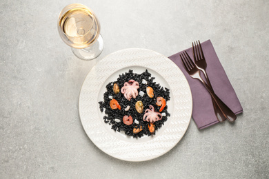 Delicious black risotto with seafood served on light grey table