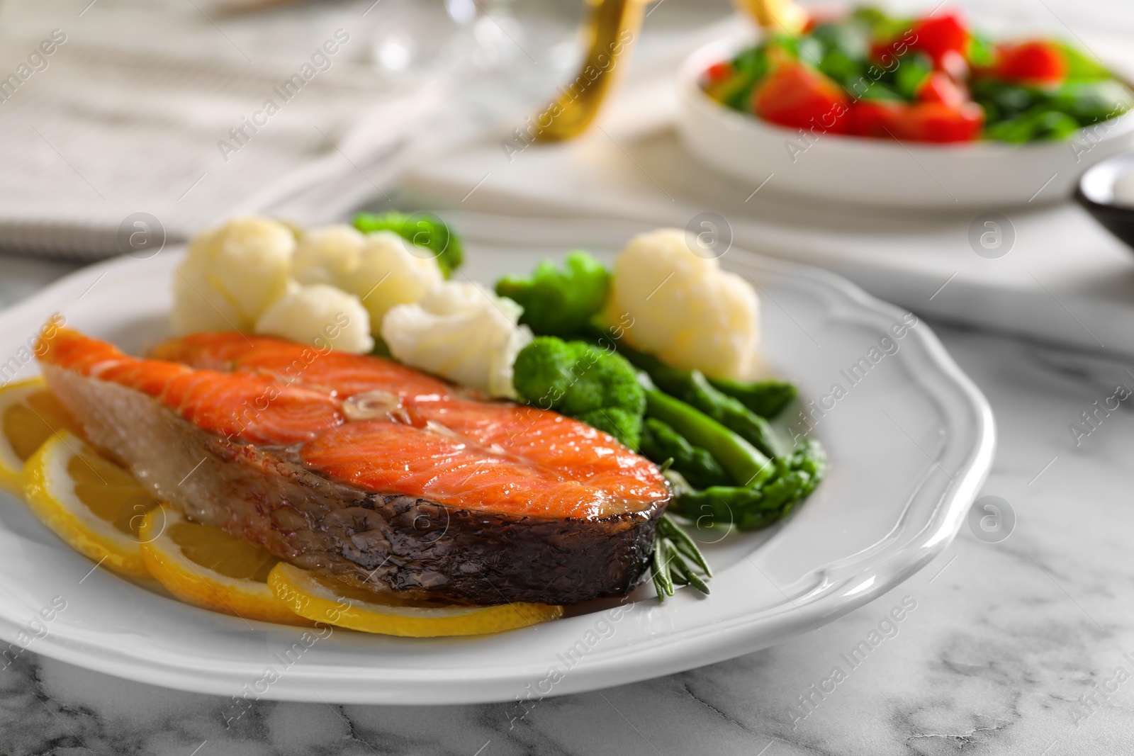 Photo of Healthy meal. Tasty grilled salmon with vegetables and lemon served on white marble table, closeup