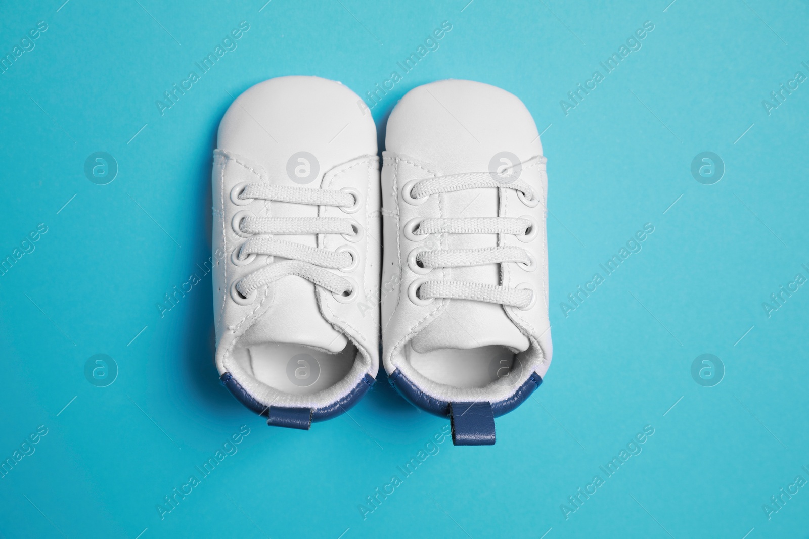 Photo of Cute baby shoes on light blue background, flat lay