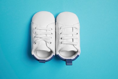 Photo of Cute baby shoes on light blue background, flat lay