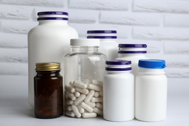 Photo of Different medical bottles on white wooden table