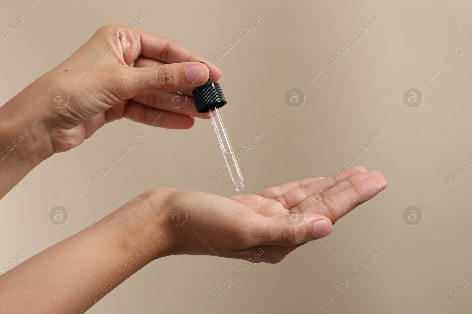 Photo of Woman applying cosmetic serum onto her hand on beige background, closeup. Space for text