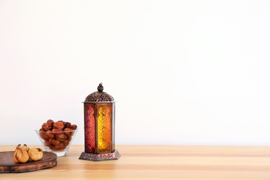 Photo of Muslim lantern Fanous and dried fruits on table against light background. Space for text