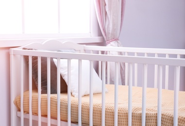 Photo of Comfortable crib in baby room. Idea for interior design