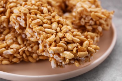 Plate with puffed rice bars (kozinaki) on grey table, closeup