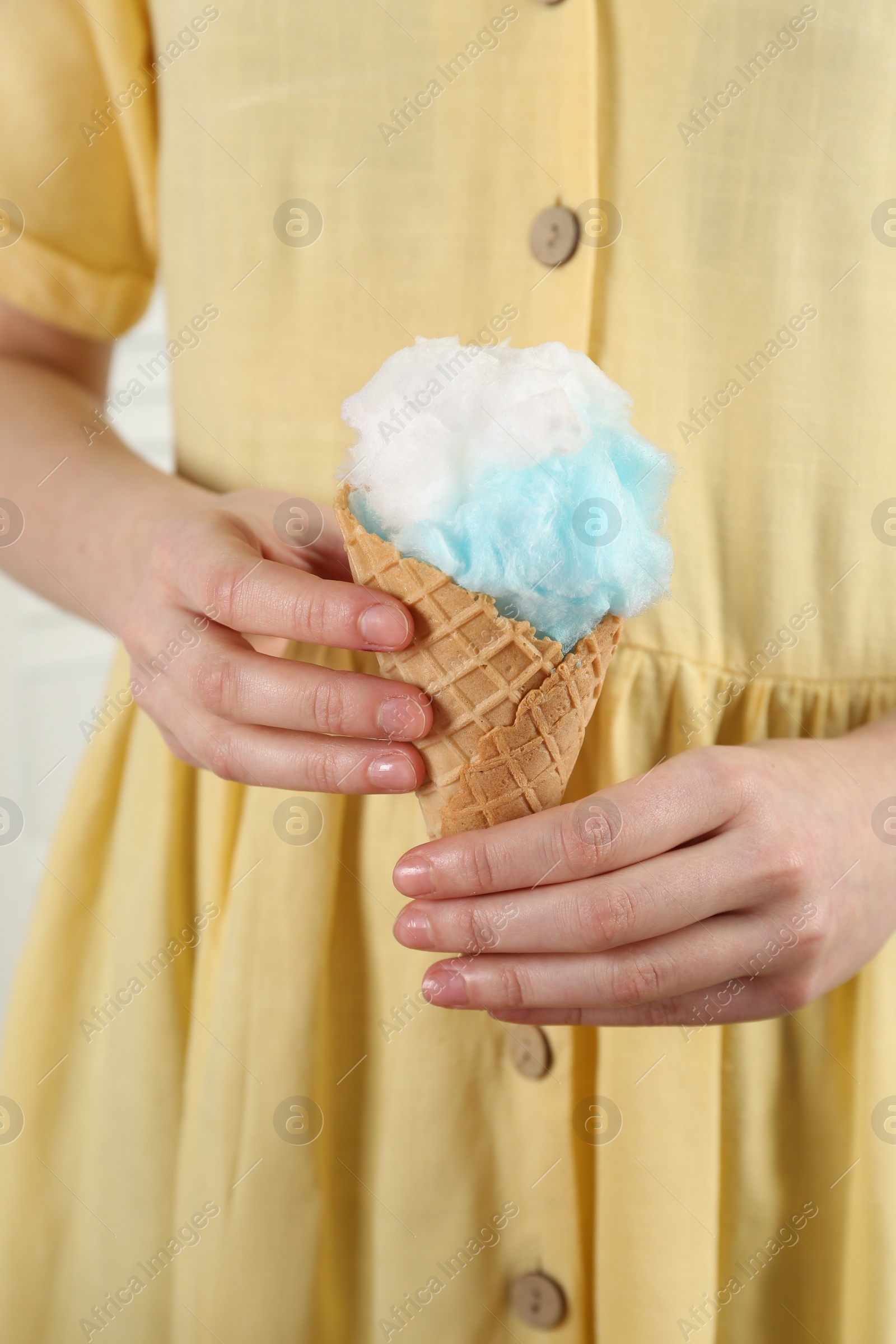 Photo of Woman holding waffle cone with cotton candy, closeup