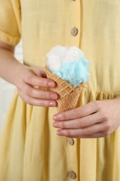 Photo of Woman holding waffle cone with cotton candy, closeup