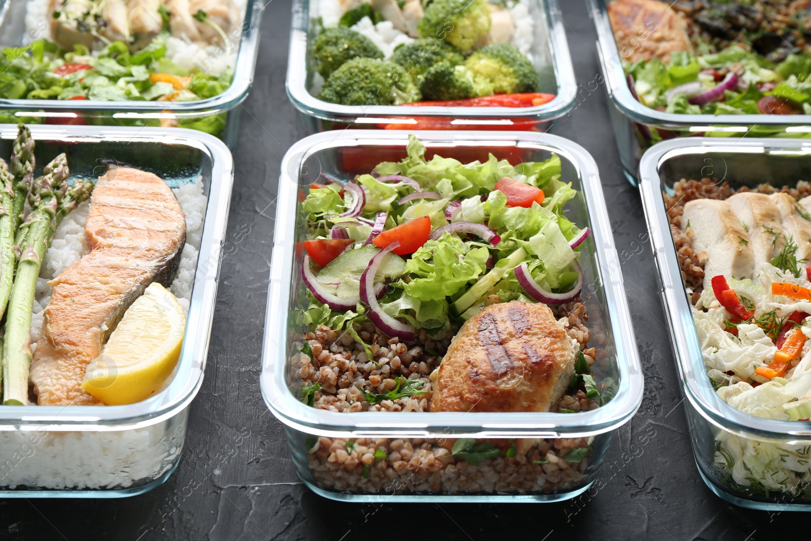 Photo of Healthy food. Different meals in glass containers on black table