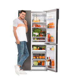 Man near open refrigerator on white background