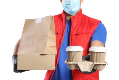 Photo of Courier in medical mask holding packages with takeaway food and drinks on white background, closeup. Delivery service during quarantine due to Covid-19 outbreak