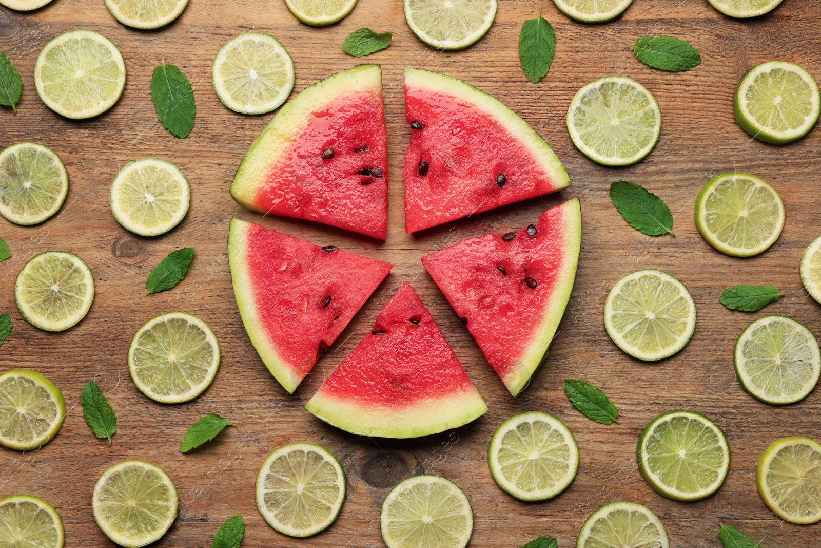 Photo of Tasty sliced watermelon and limes on wooden table, flat lay