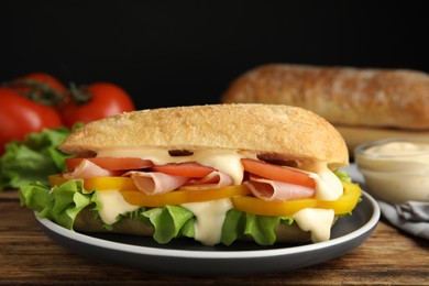 Delicious sandwich with vegetables, ham and mayonnaise served on wooden table, closeup