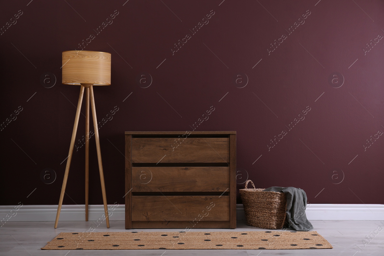Photo of Elegant room interior with stylish chest of drawers, floor lamp and wicker basket
