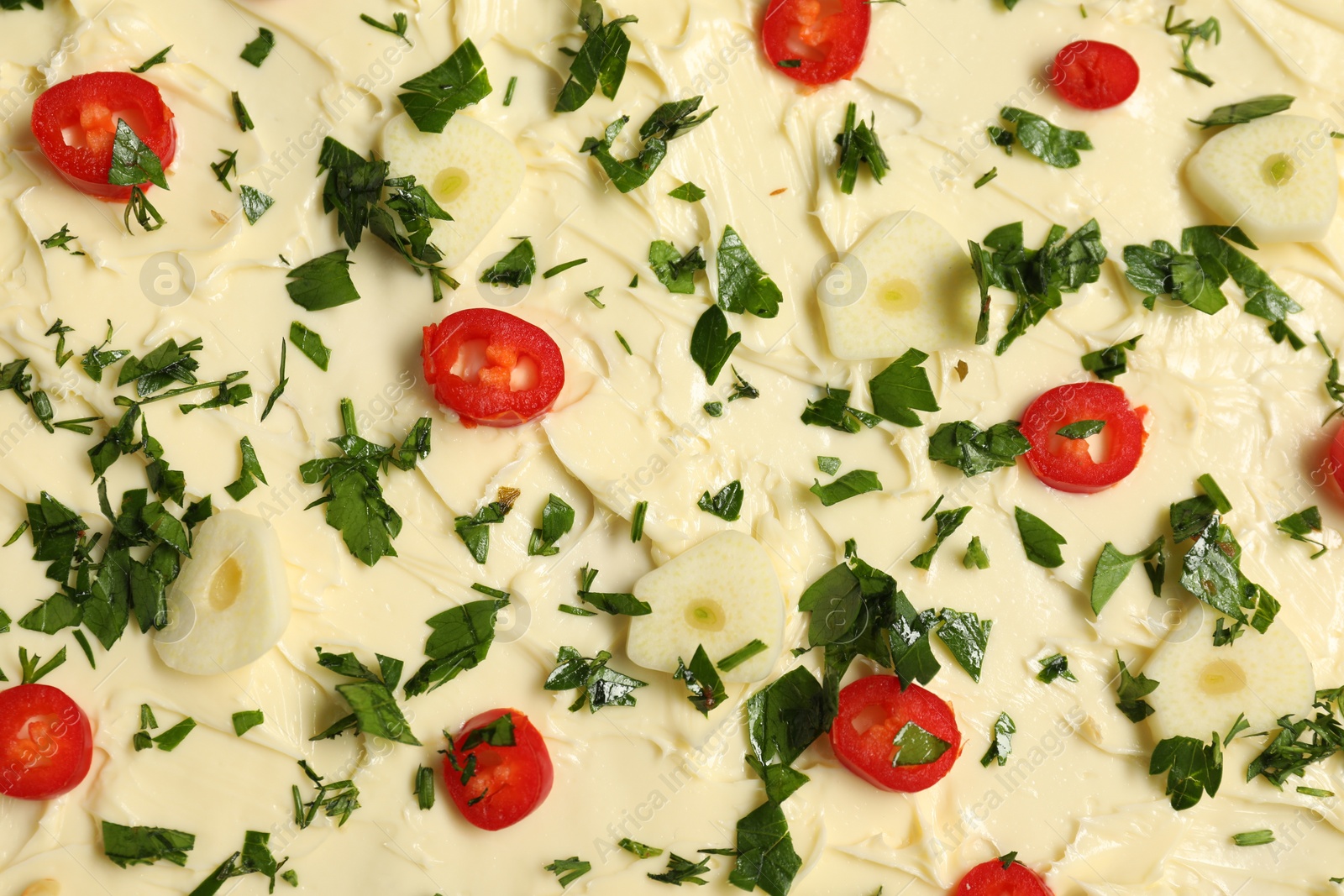 Photo of Fresh natural butter with cut pepper, garlic and parsley as background, top view