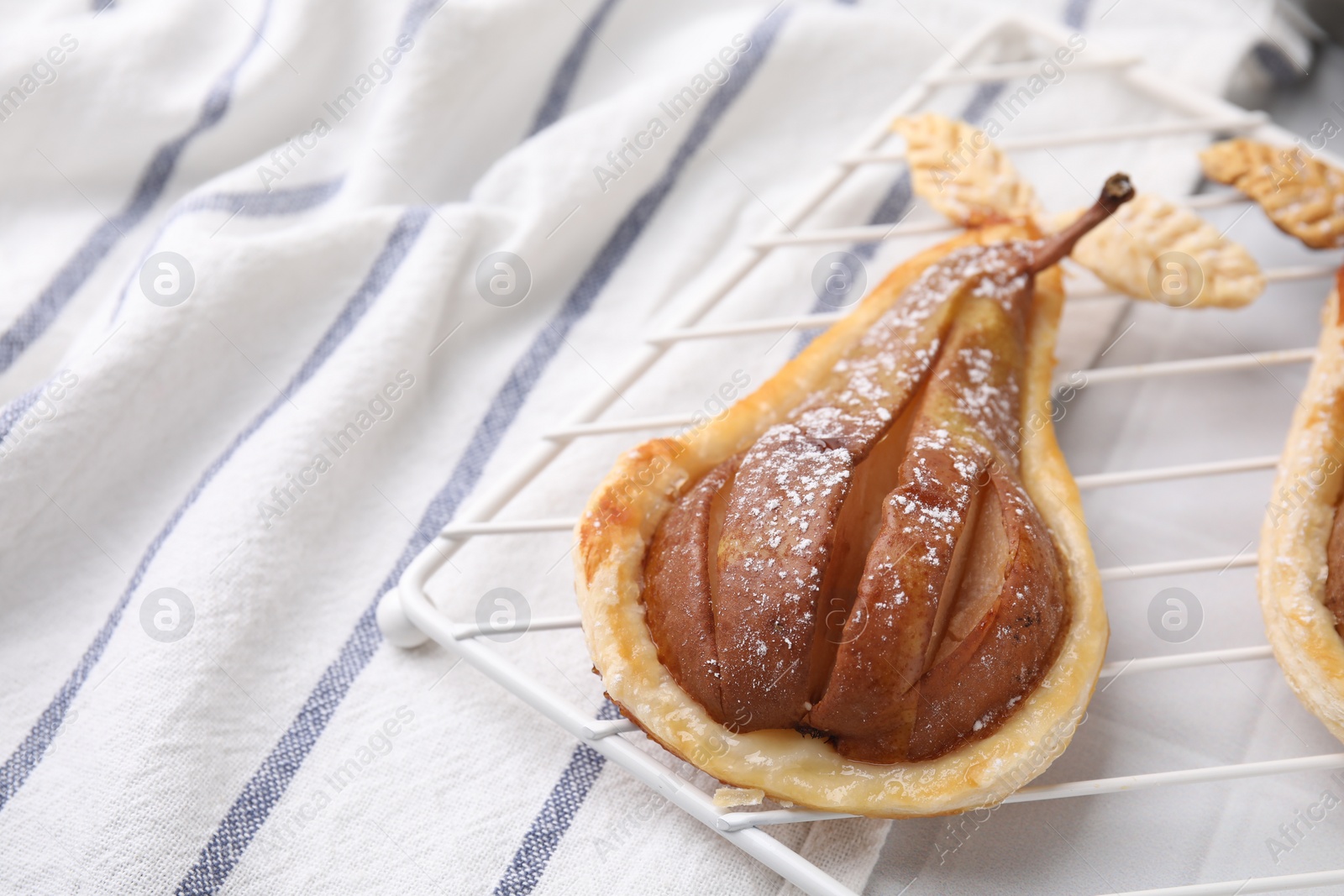 Photo of Delicious pear baked in puff pastry with powdered sugar on table, closeup. Space for text