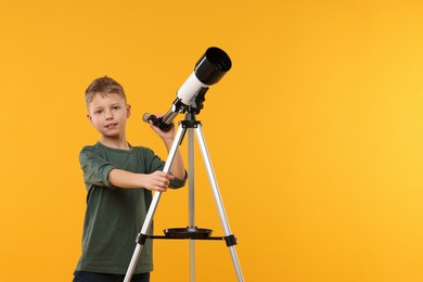 Photo of Cute little boy with telescope on orange background, space for text