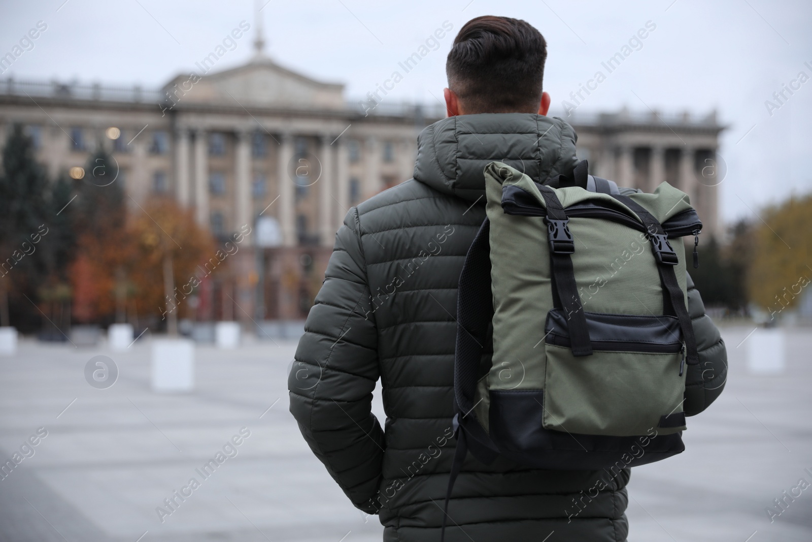 Photo of Male tourist with travel backpack on city street, back view. Urban trip