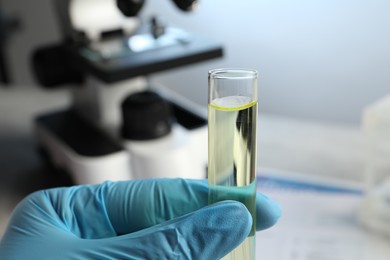 Doctor holding test tube with urine sample for analysis in laboratory, closeup