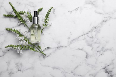 Photo of Bottle of essential oil and flowers on white marble table, flat lay. Space for text