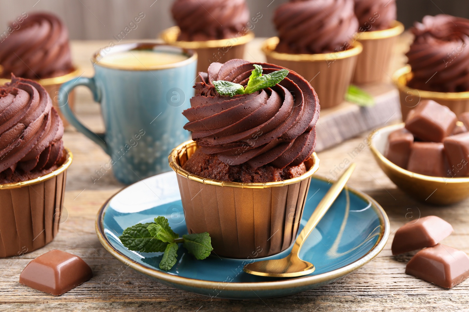 Photo of Delicious cupcakes with mint and chocolate pieces on wooden table, closeup