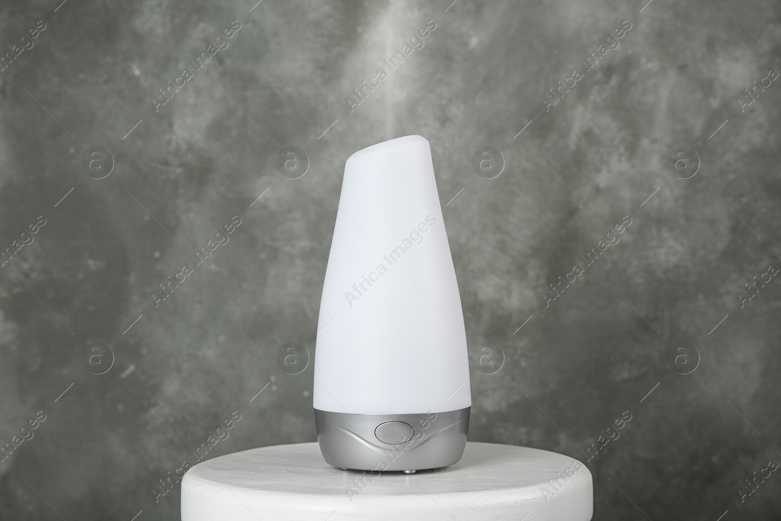 Photo of Modern essential oil diffuser on white table against grey background