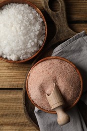 Photo of Different natural salt on wooden table, flat lay