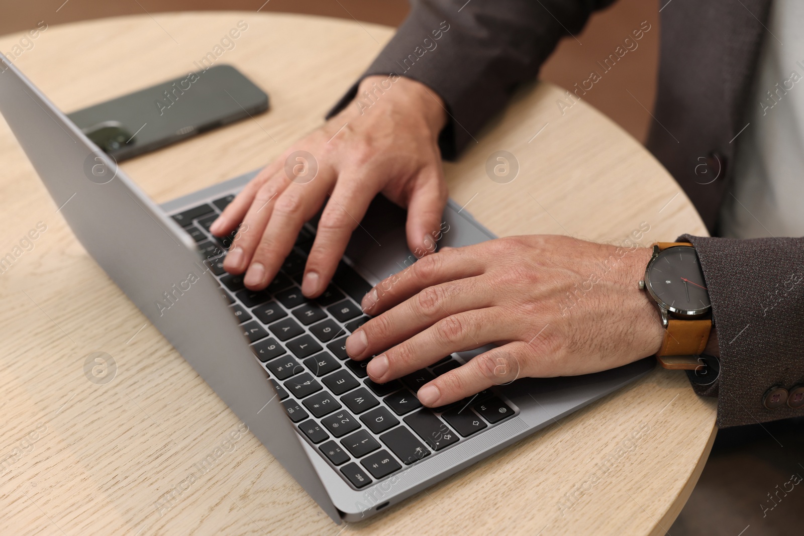 Photo of Man using laptop at wooden table, closeup