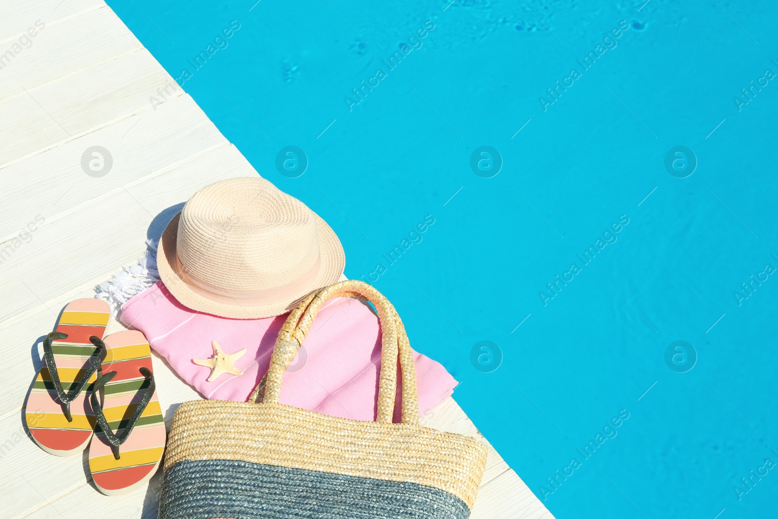 Photo of Beach accessories on wooden deck near swimming pool. Space for text