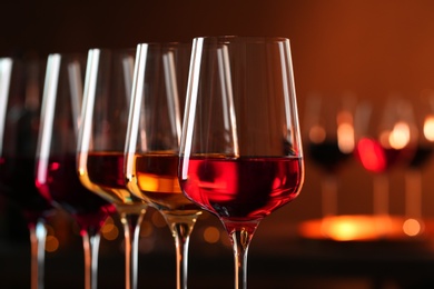 Photo of Row of glasses with different wines against blurred background, closeup. Space for text