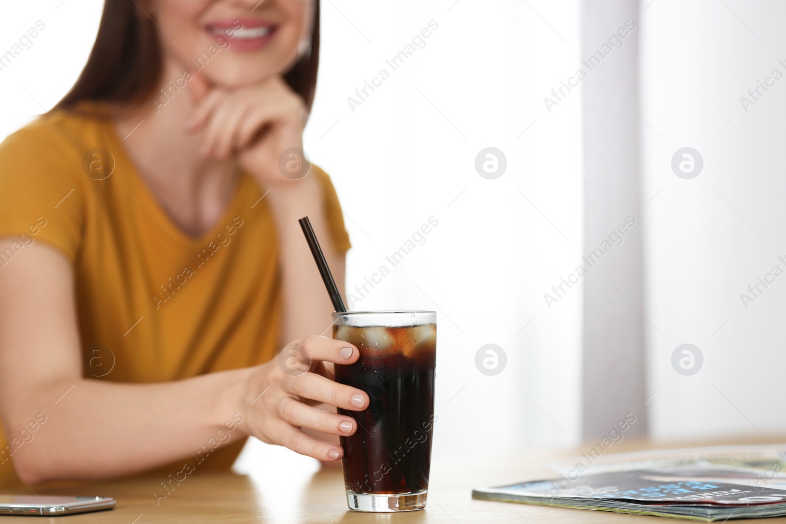 Photo of Young woman with glass of cola at table, closeup. Refreshing drink