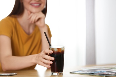 Photo of Young woman with glass of cola at table, closeup. Refreshing drink