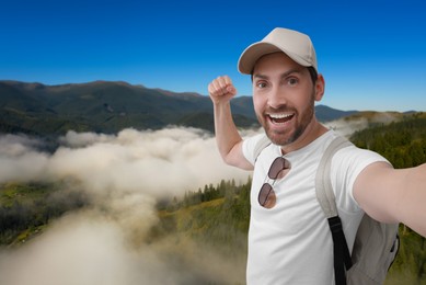 Image of Smiling man taking selfie in misty mountains