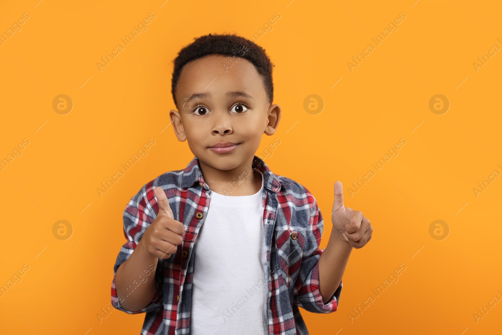 Photo of African-American boy showing thumbs up on orange background