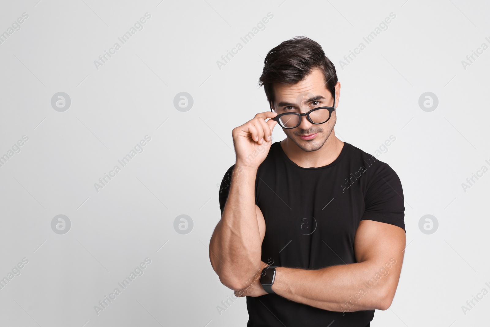 Photo of Portrait of handsome young man in black t-shirt with glasses on grey background. Space for text