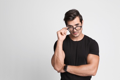 Photo of Portrait of handsome young man in black t-shirt with glasses on grey background. Space for text