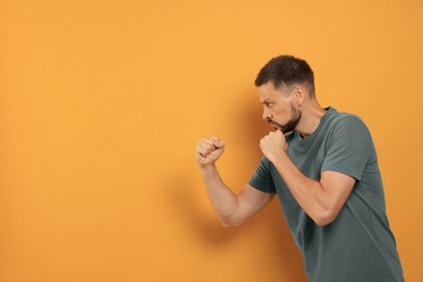 Photo of Man ready to fight on orange background, space for text
