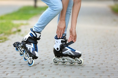 Photo of Woman fixing roller skates in park, closeup