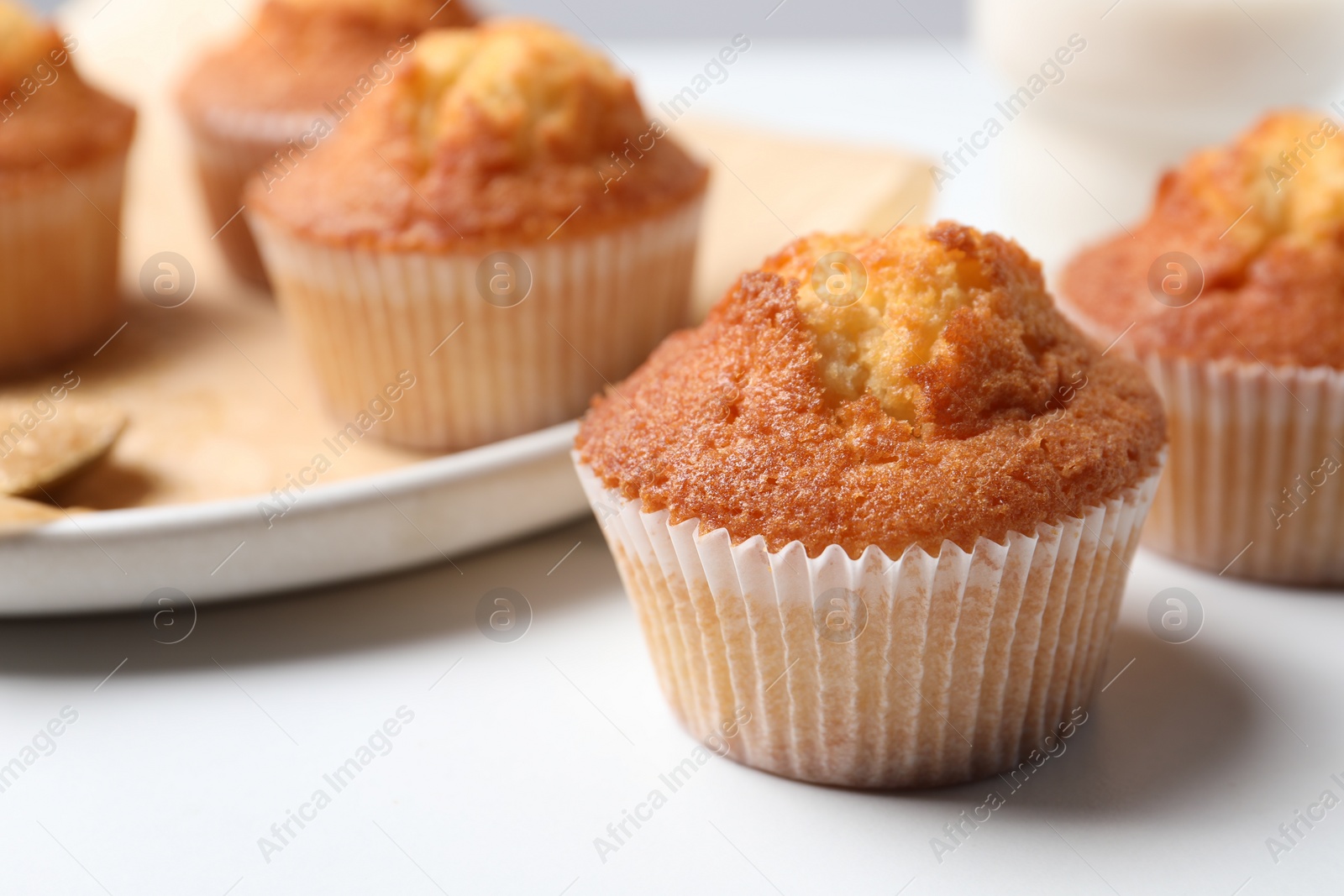 Photo of Delicious sweet muffins on white table, closeup. Space for text