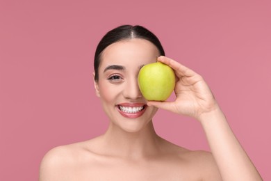 Photo of Beautiful young woman with apple on pink background