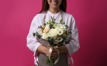 Photo of Florist holding beautiful wedding bouquet on pink background, closeup