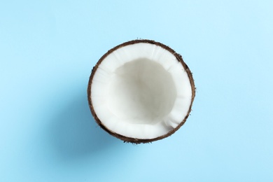 Half of coconut on color background, top view