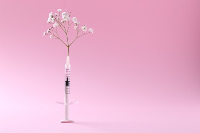 Photo of Cosmetology. Medical syringe and gypsophila on pink background, space for text