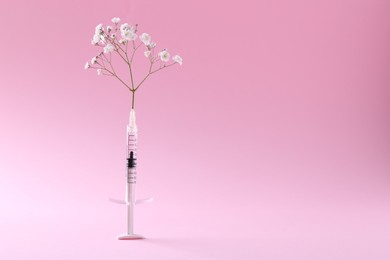 Cosmetology. Medical syringe and gypsophila on pink background, space for text