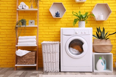 Laundry room interior with modern washing machine near yellow brick wall