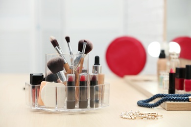 Photo of Organizer with cosmetic products and makeup accessories on dressing table