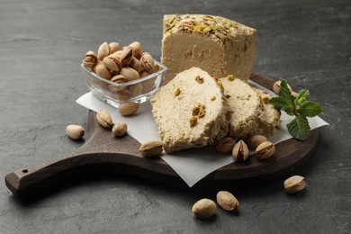 Photo of Tasty halva with pistachios and mint on grey table